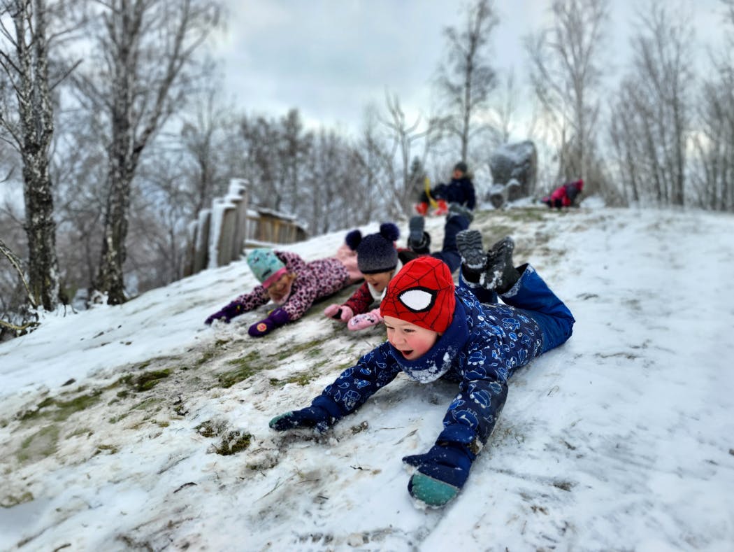 Kinder im Schnee am Rutschen